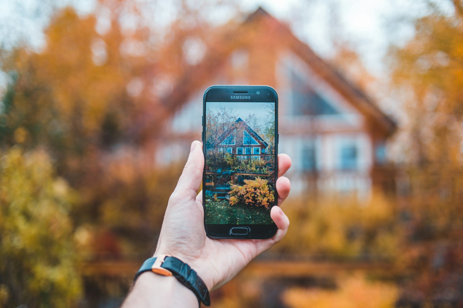 Browsing a home listing on a phone in front of the house