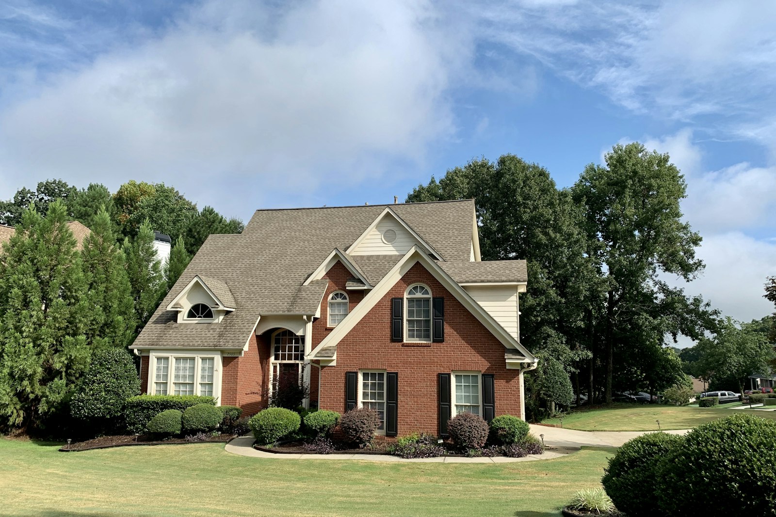 Brick two-story home with a green lawn and trees